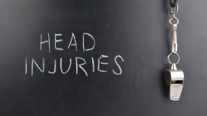 Head injuries written on a chalkboard, with a whistle hanging on the side